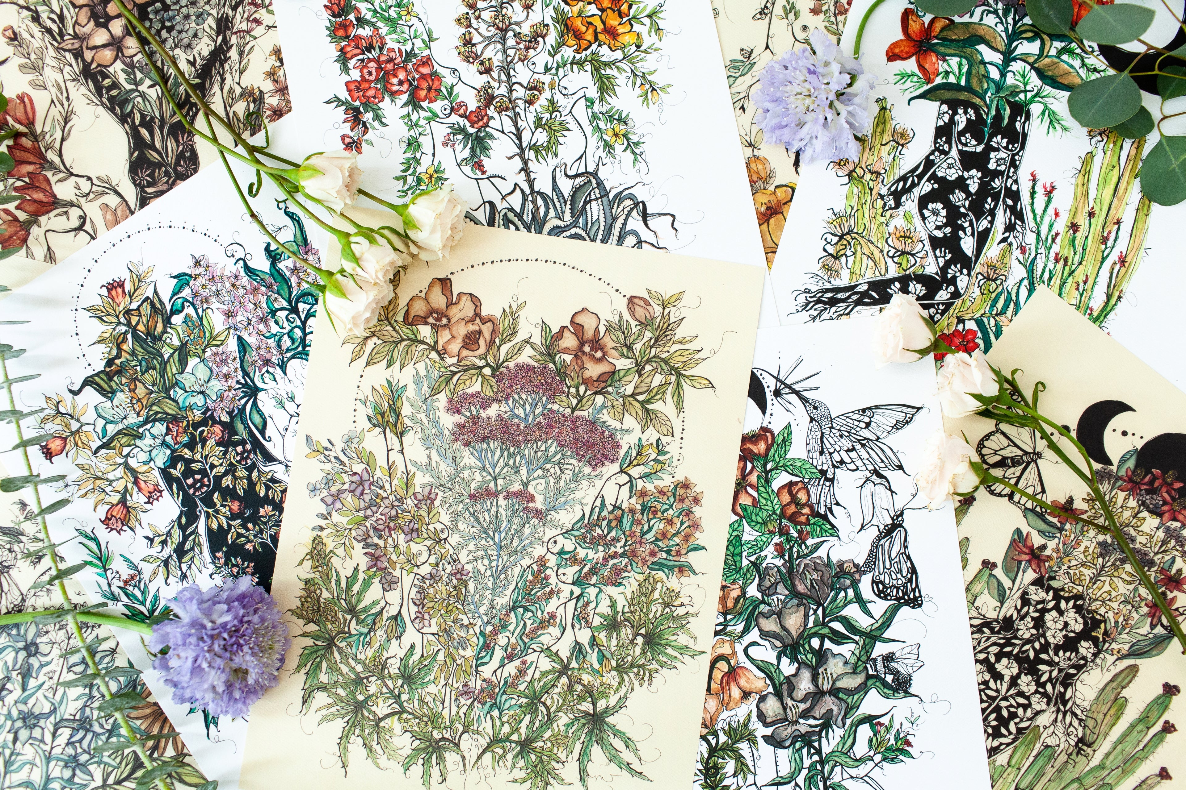 a pile of fine art prints from the artist marcy ellis depicting the female form surrounded by growing florals, plants and hummingbirds. 