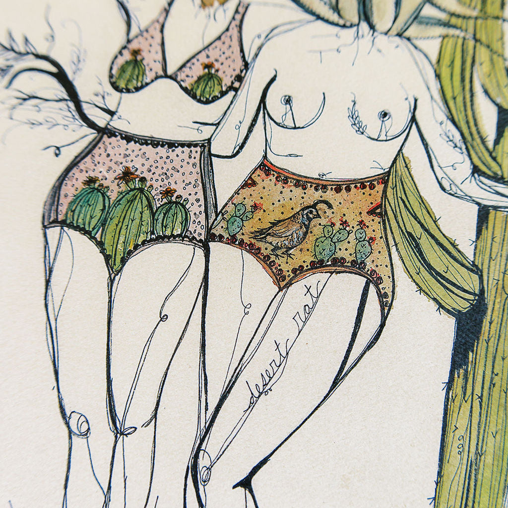 Details of watercolor art print of two feminine figures in swimsuits among desert cacti and flowers on a textured beige backgroun