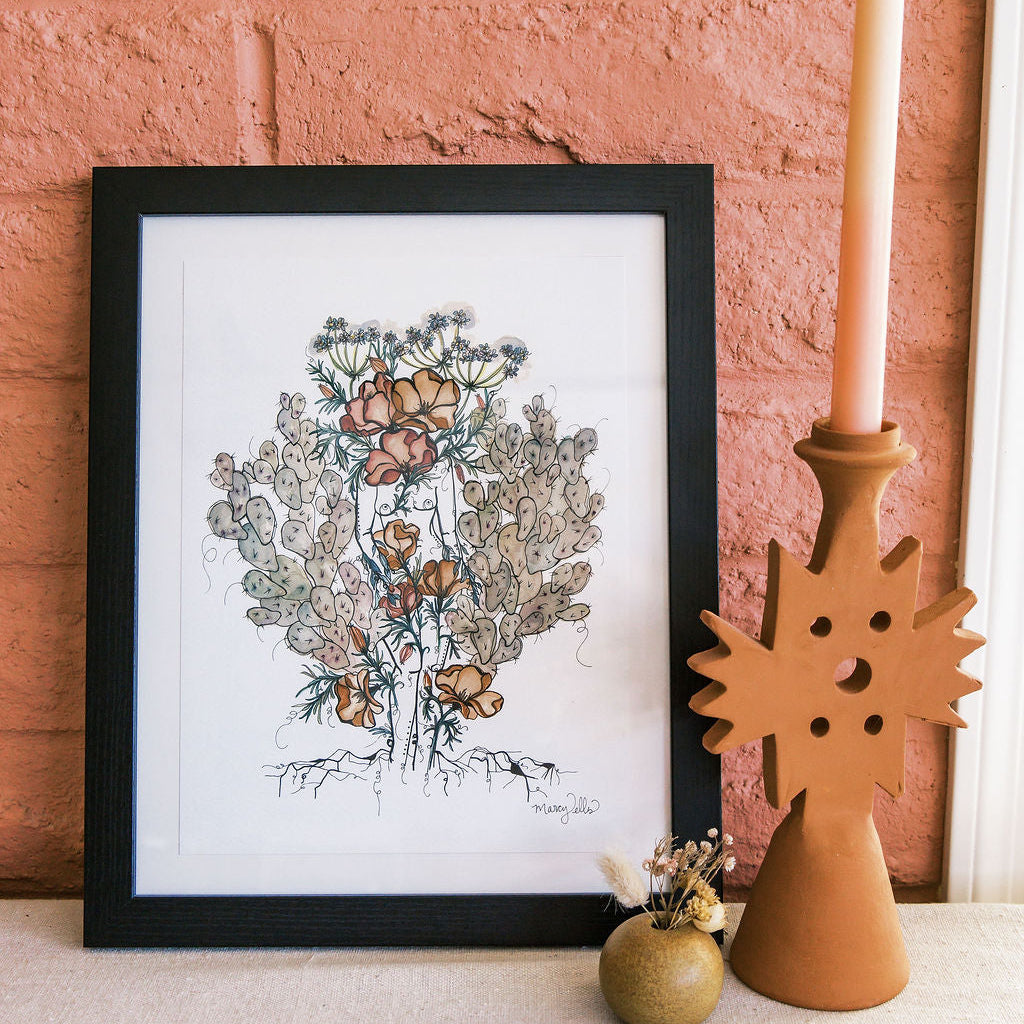Framed watercolor art print of a feminine figure standing atop mountains with orange poppies and purple prickly pear cacti in a desert landscape