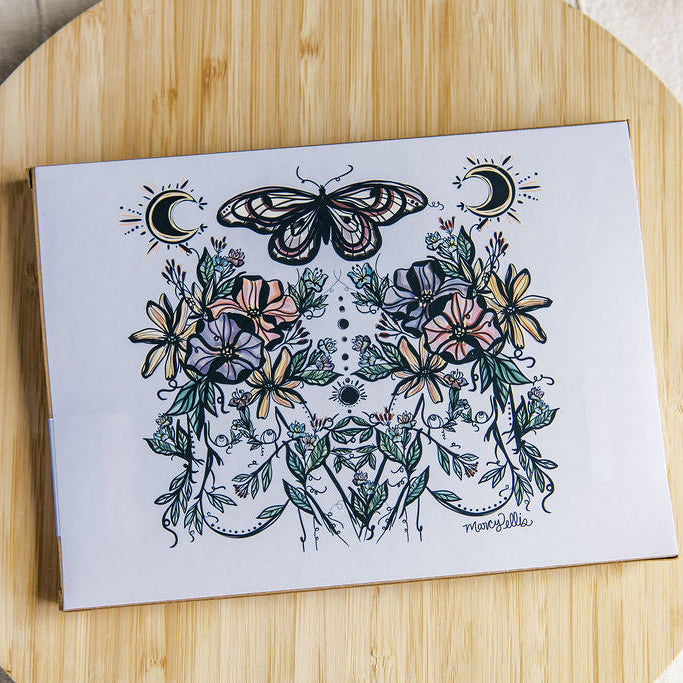 the back of the Kraft puzzle box featuring two botanical women with butterfly and moon phases by Marcy Ellis. 