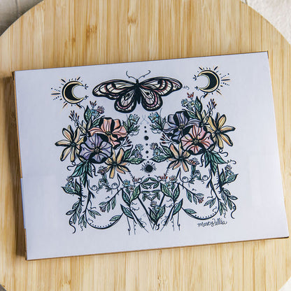 the back of the Kraft puzzle box featuring two botanical women with butterfly and moon phases by Marcy Ellis. 