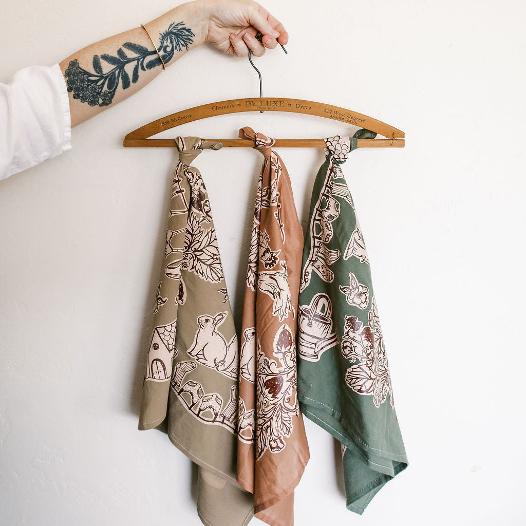 Three patterned scarves hanging on a wooden hanger against a white background