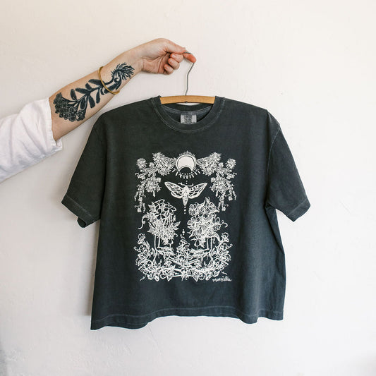 Black t-shirt with white graphic design on a hanger against a plain background