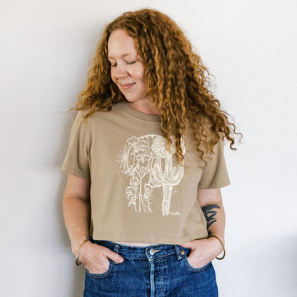 woman wearing a sand boxy crop tee hand screen printed with an ivory crested saguaro and botanical figure design by marcy ellis
