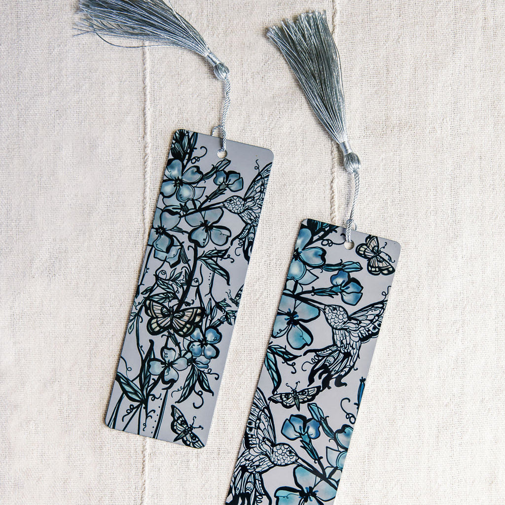 two metal bookmarks with hummingbirds and botanical figure in blue by Marcy Ellis. 