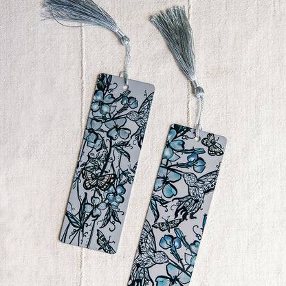 two metal bookmarks with hummingbirds and botanical figure in blue by Marcy Ellis. 