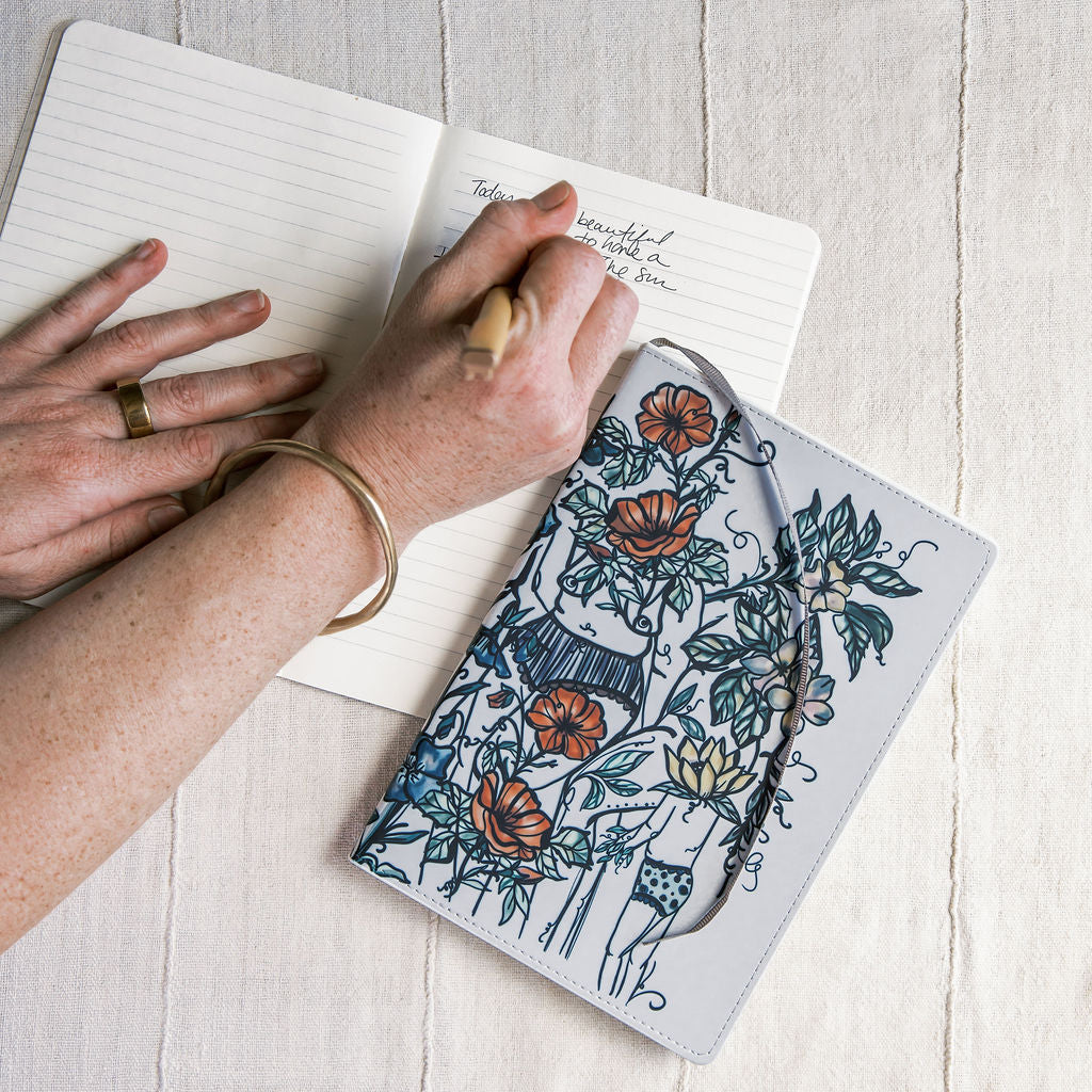 a5 lined journal with watercolor feminine botanical figures wrapping the front and back covers. 190 pages, faux leather cover. hand-painted design by artist Marcy Ellis in Tucson, AZ.