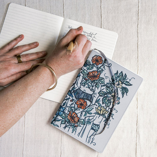 a5 lined journal with watercolor feminine botanical figures wrapping the front and back covers. 190 pages, faux leather cover. hand-painted design by artist Marcy Ellis in Tucson, AZ.