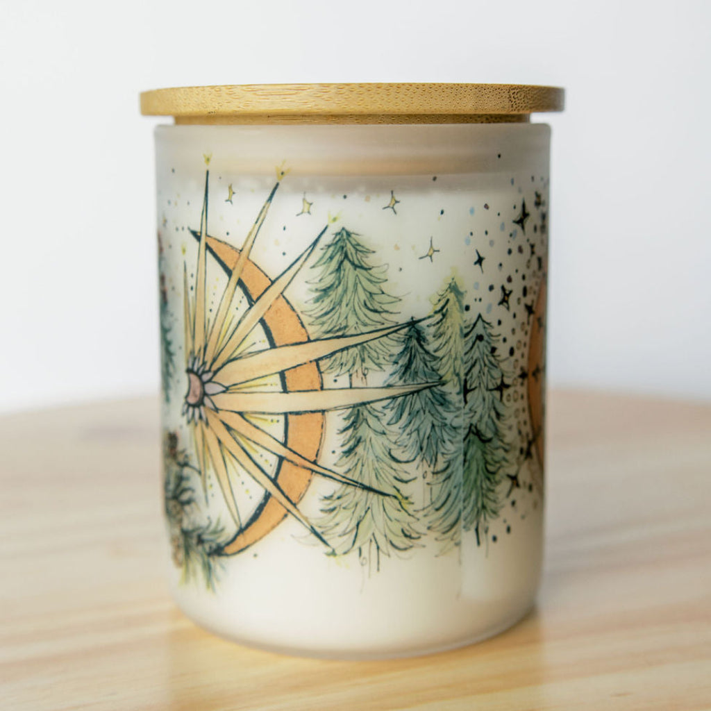 bamboo lid on yule winter solstice soy candle with botanical artwork wrapped around frosted glass jar