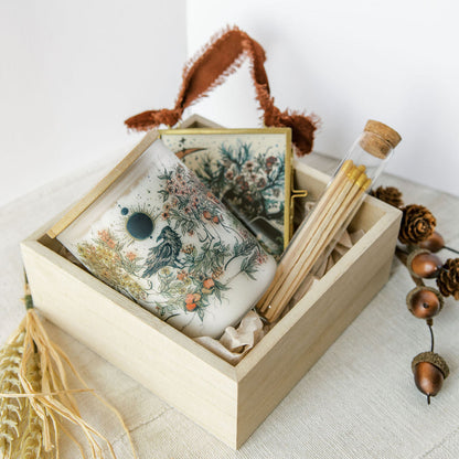 botanical candle, glass ornament and matches packed in a wooden gift box, held by marcy ellis