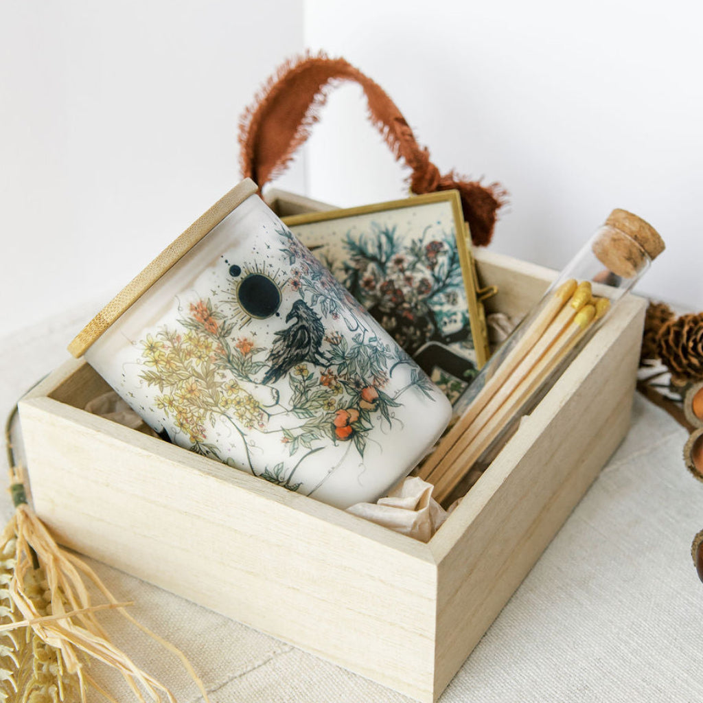 botanical candle, glass ornament and matches packed in a wooden gift box, held by marcy ellis