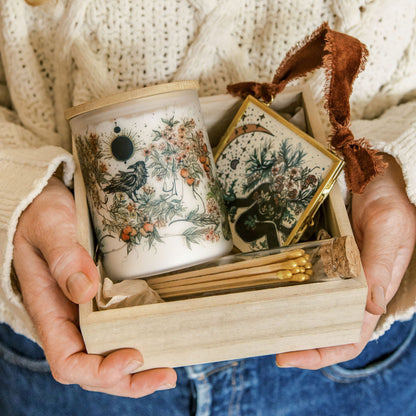 botanical candle, glass ornament and matches packed in a wooden gift box, held by marcy ellis