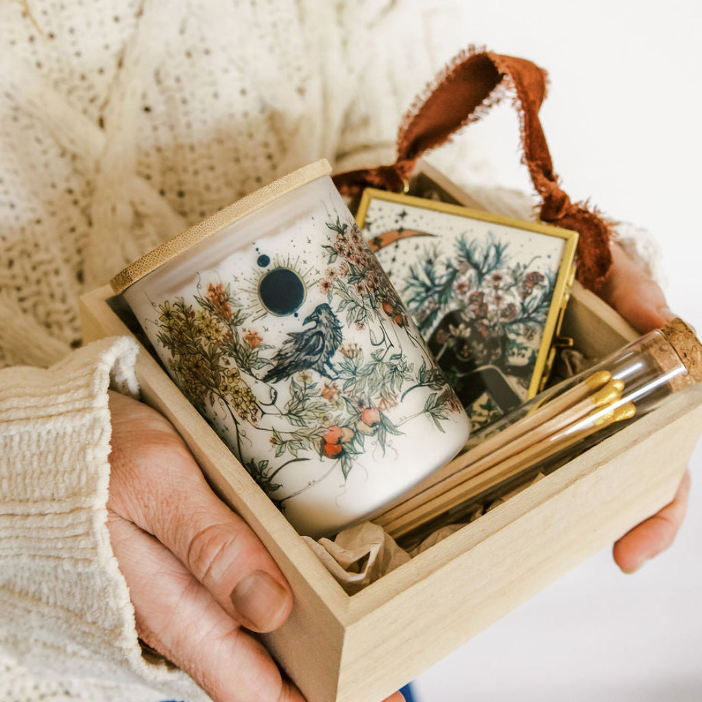 botanical candle, glass ornament and matches packed in a wooden gift box, held by marcy ellis