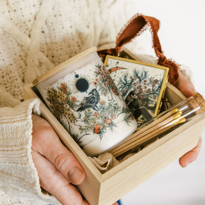 botanical candle, glass ornament and matches packed in a wooden gift box, held by marcy ellis