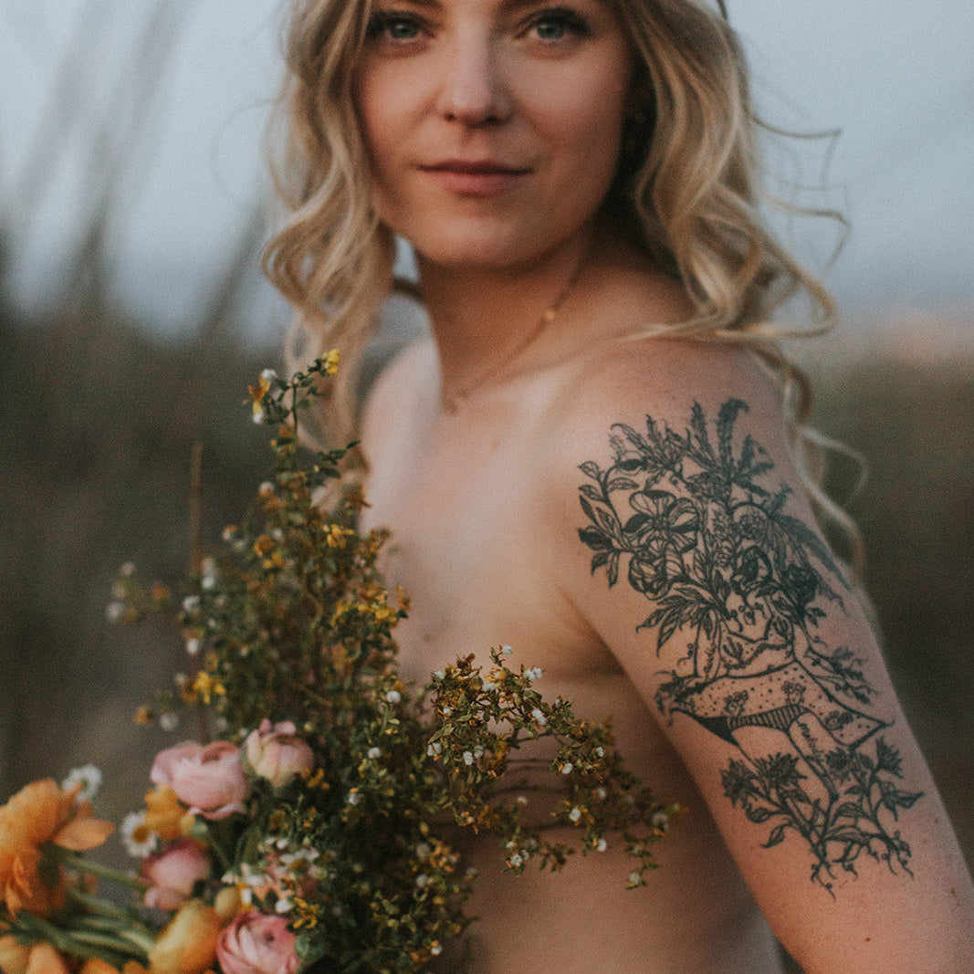 fine line tattoo of a female plant lady botanical figures by marcy ellis on upper arm, framed by dried florals