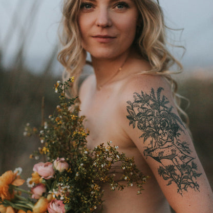 fine line tattoo of a female plant lady botanical figures by marcy ellis on upper arm, framed by dried florals